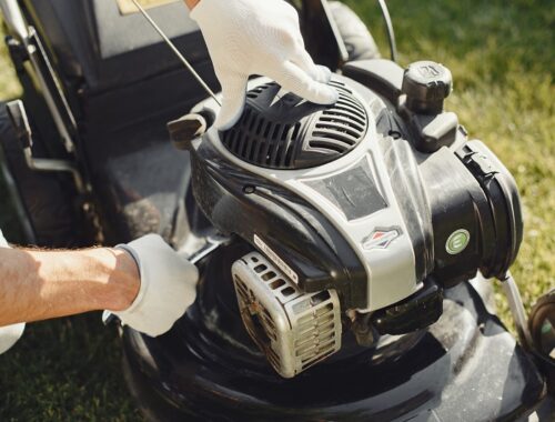 Lawn equipment maintenance worker inspecting a lawn mower engine outdoors