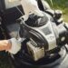 Lawn equipment maintenance worker inspecting a lawn mower engine outdoors